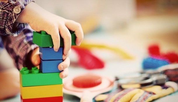 Betreuung - Das Bild zeigt ein Kind beim Spielen mit Bauklötzen.